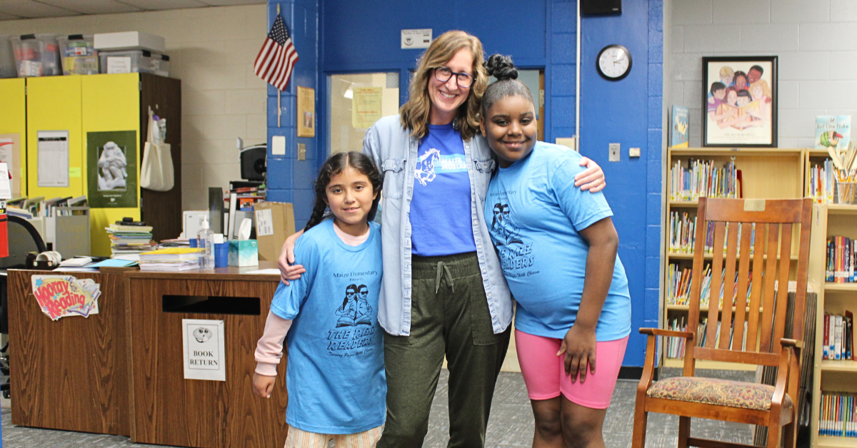 teacher wrapping arms around two students